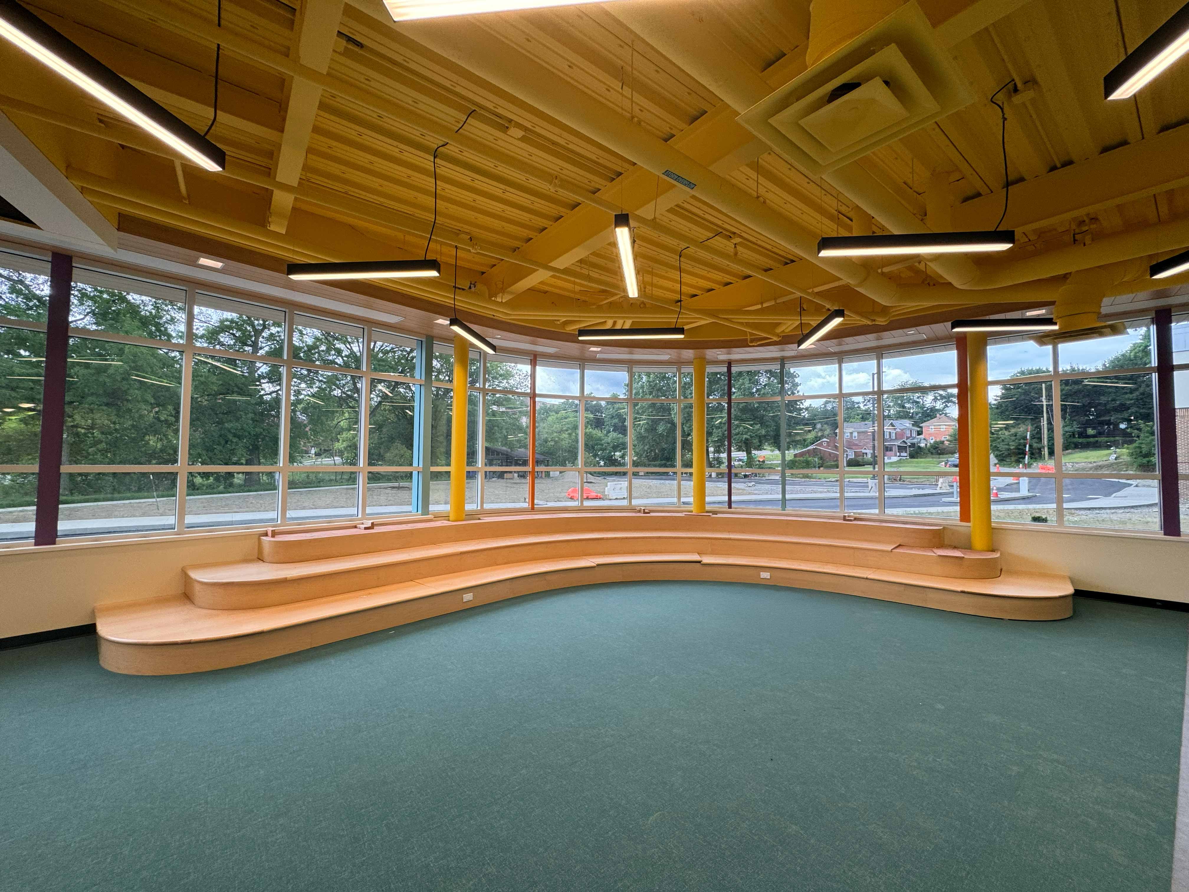 Elementary school media center with curved wooden stairs and colorful accents