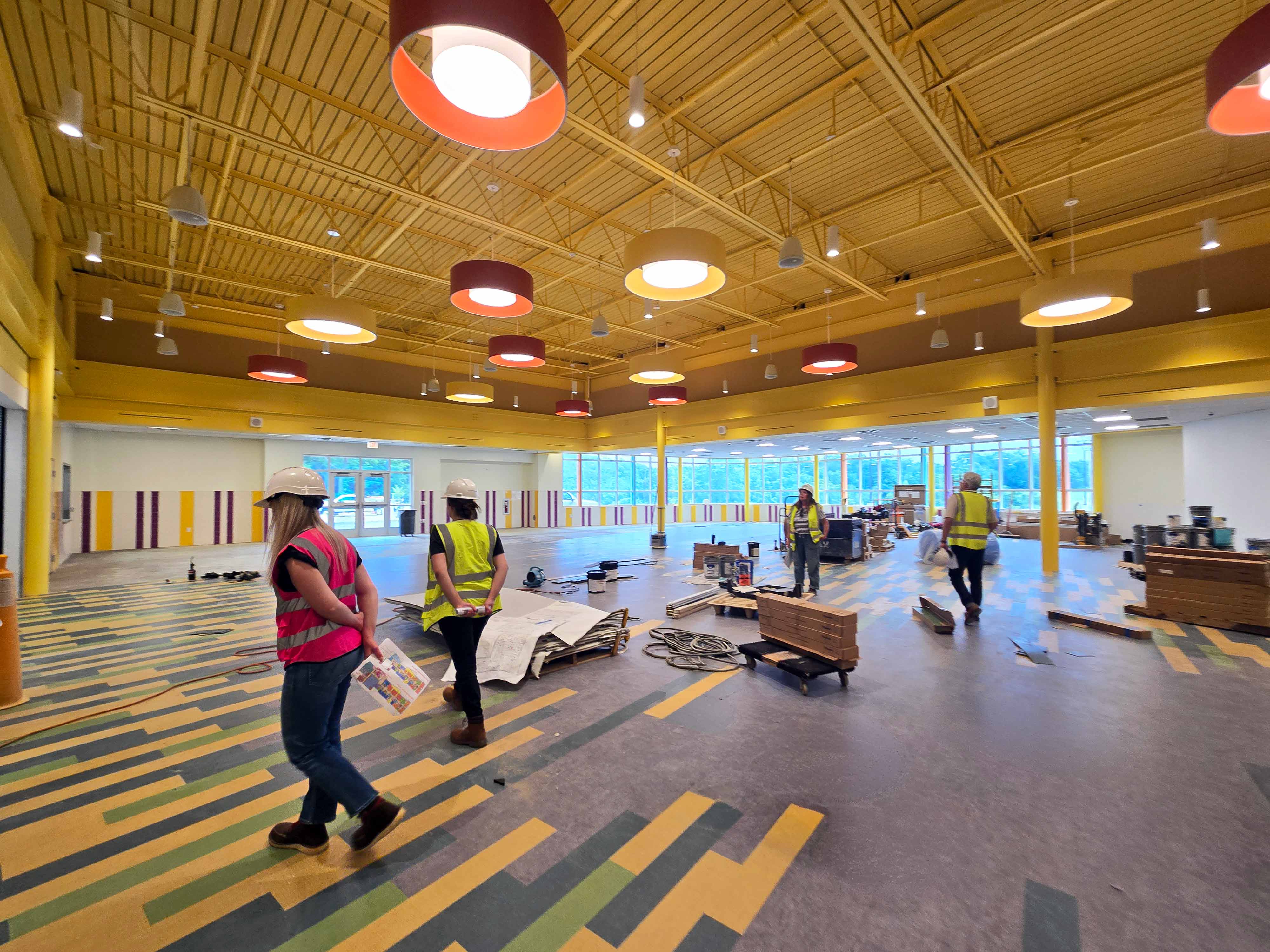 Elementary school cafeteria with bright colors, circular light fixtures, and large windows