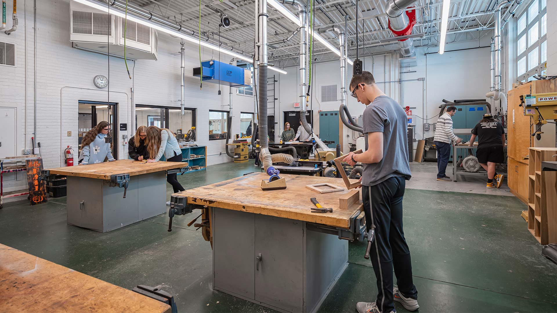 High School wood shop classroom with students collaborating on wood building projects